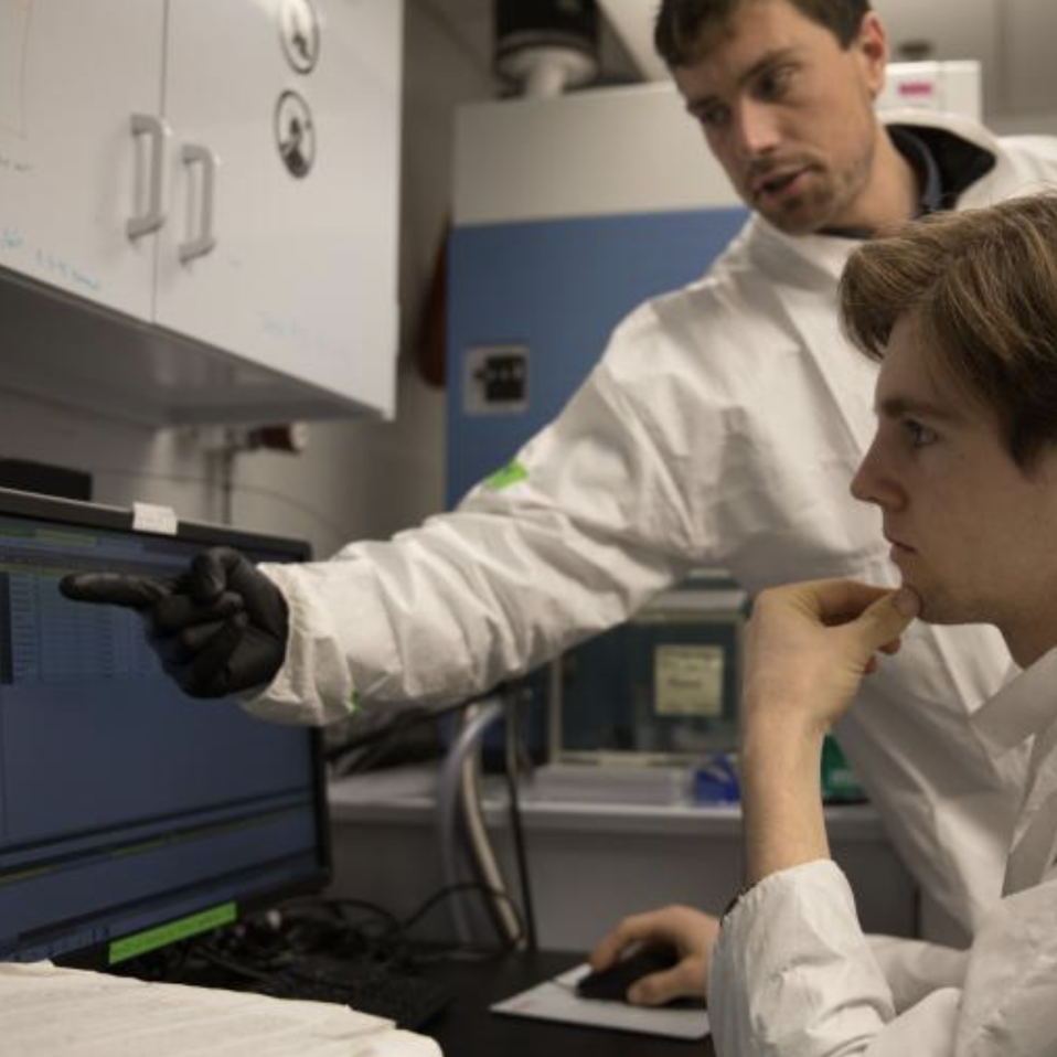 This photo shows a student working in lab with his mentor.